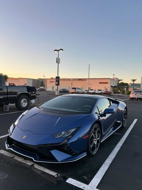 Blue Lamborghini sports car parked in a parking lot at sunset